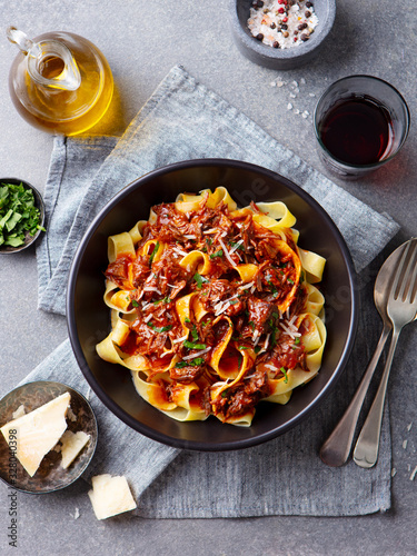 Pasta pappardelle with beef ragout sauce in black bowl. Grey background. Top view. photo