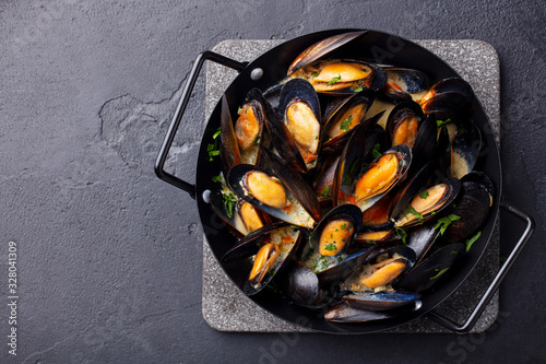 Canvas Print Mussels with herbs and sauce in black pan