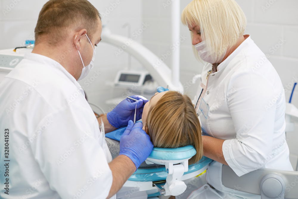 Doctor dentist treats teeth of a beautiful young girl patient. The girl on reception at the dentist. Doctor dentist treats tooth Doctor dentist treats teeth of a beautiful young girl patient. The girl on reception at the dentist. Doctor dentist treats tooth
