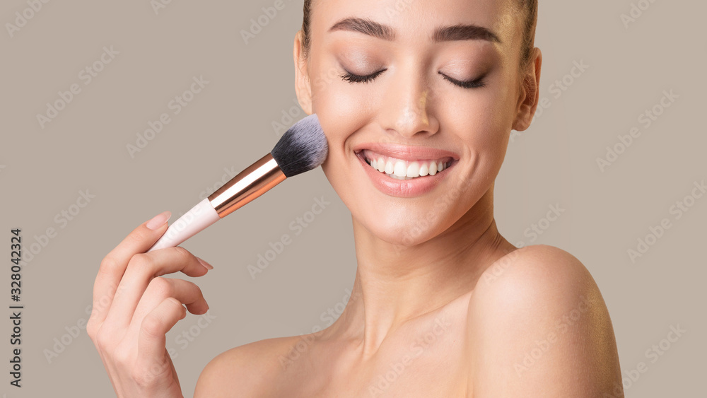 Attractive Woman Applying Face Powder On Beige Studio Background, Panorama Attractive Woman Applying Face Powder On Beige Studio Background, Panorama