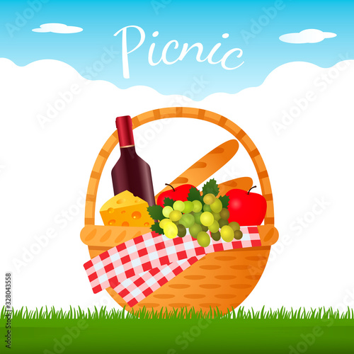tasty wicker picnic basket with a bottle of red wine, fruit and cheese on green grass.