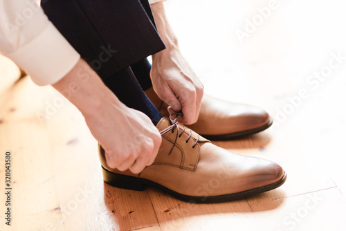 A groom putting on cuff-links as he gets dressed in formal wear .