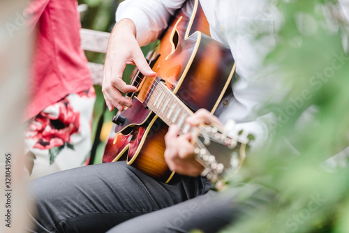 close up finger of guitarist while playing guitar in the outdoor garden