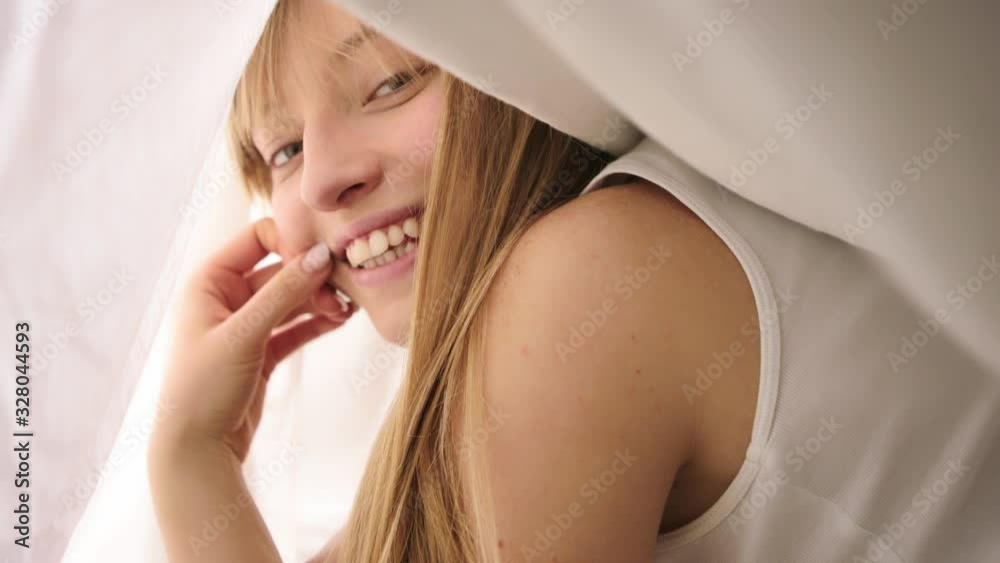Smiling attractive woman under white duvet in her bedroom. Smiling attractive woman under white duvet in her bedroom.