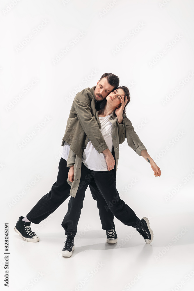 Supporting. Trendy fashionable couple isolated on white studio background. Caucasian woman and man posing in basic minimal stylish clothes. Concept of relations, fashion, beauty, love. Copyspace. Supporting. Trendy fashionable couple isolated on white studio background. Caucasian woman and man posing in basic minimal stylish clothes. Concept of relations, fashion, beauty, love. Copyspace.