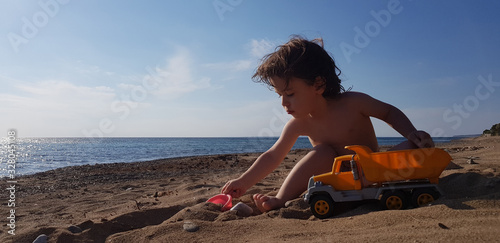 a little boy playing with toy truck on the beach