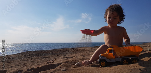 a little boy playing with toy truck on the beach