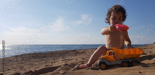 a little boy playing with toy truck on the beach