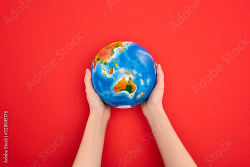 Cropped view of woman holding globe on red background  global warming concept