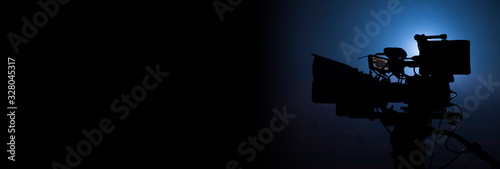 video camera silhouette in the dark banner with blue light, movie or television background
