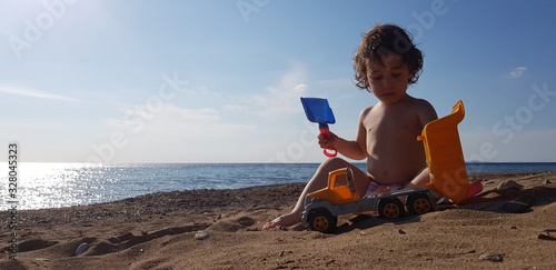 a little boy playing with toy truck on the beach