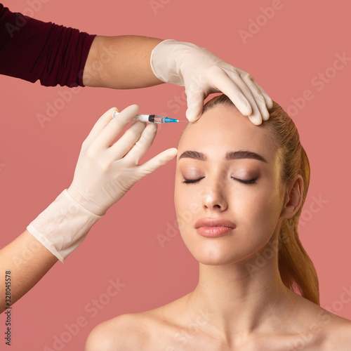 Woman Getting Beauty Injection In Forehead Smoothing Skin, Pink Background