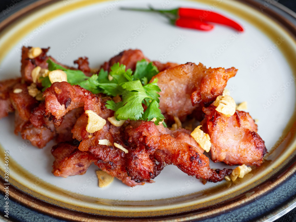 Fried Pork with Garlic Thai food Ingredients of pork ribs,Decorate the dish with red chilies, garlic and coriander on a white plate.