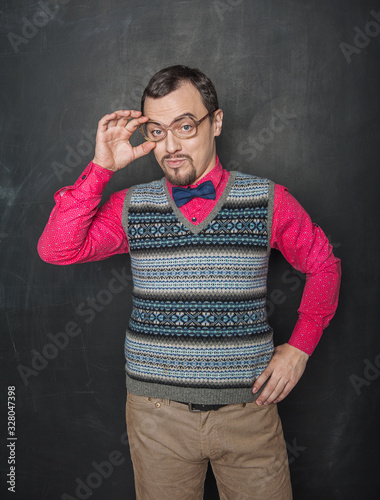 Funny retro style teacher in eyeglasses looking at you on blackboard