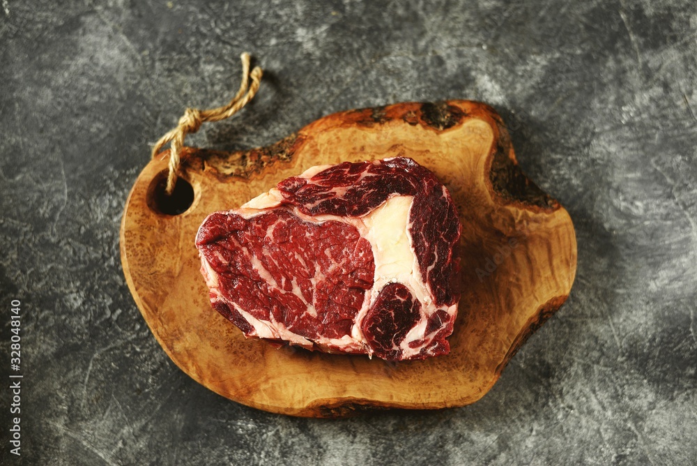 Obraz premium Fresh raw rib eye steak on a wooden board. Organic food.