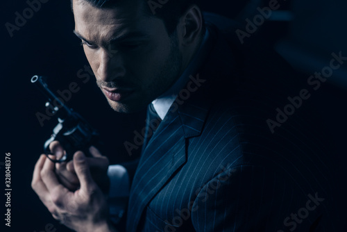 Gangster with revolver in clenched hands on dark background