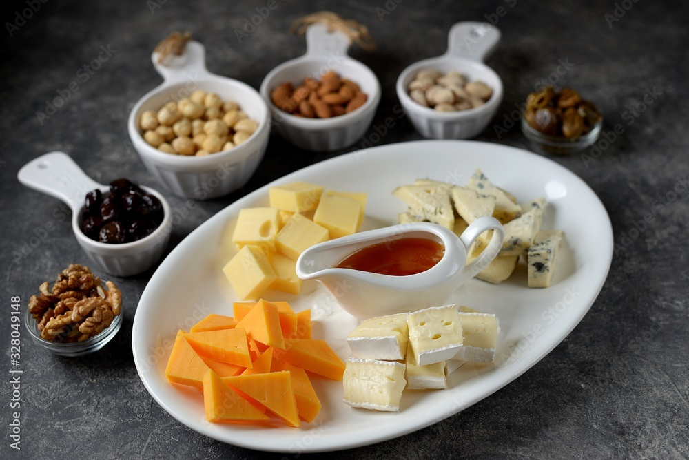 Various types of cheeses with olives, nuts, fruits and honey. Appetizer for a wine party.