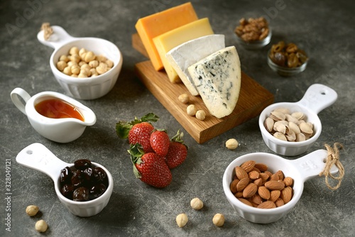 Various types of cheeses with olives, nuts, fruits and honey. Appetizer for a wine party.