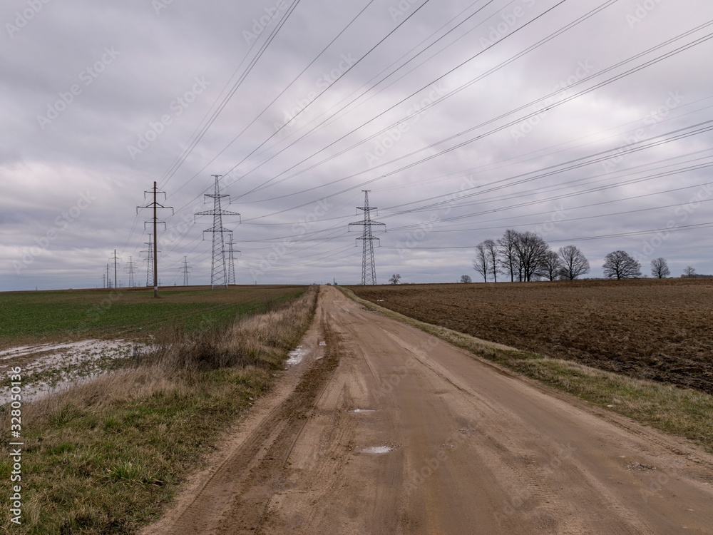 landscape with wet earth road and high voltage line