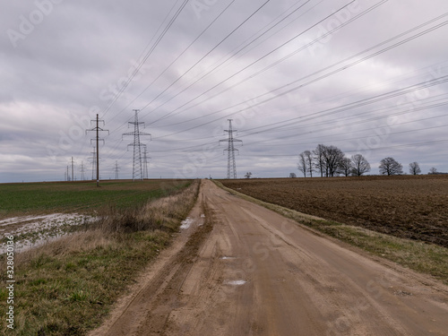 landscape with wet earth road and high voltage line