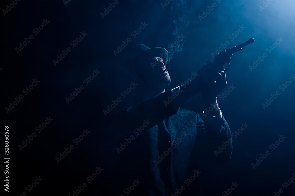 Silhouette of gangster aiming revolver and smoking on dark background Silhouette of gangster aiming revolver and smoking on dark background