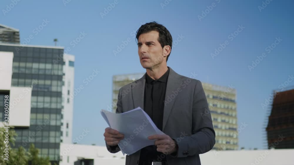 Businessman reading documents on street. Male manager looking business papers Businessman reading documents on street. Male manager looking business papers