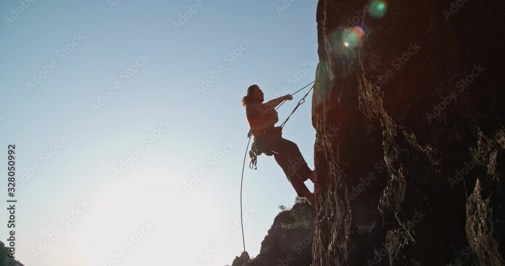 Experiensed caucasian mountaineer is dragging special ropes while climbing up a steep cliff, doing extreme sports - extreme tourism concept 4k footage