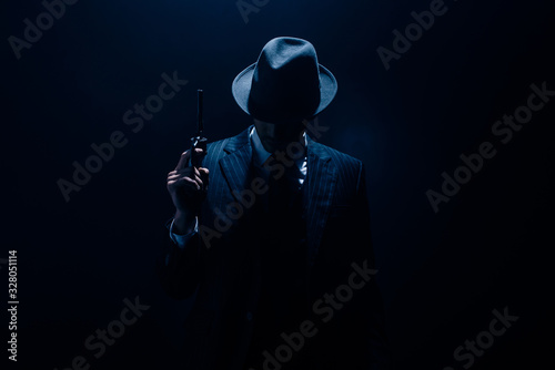 Silhouette of gangster raising gun on dark blue background