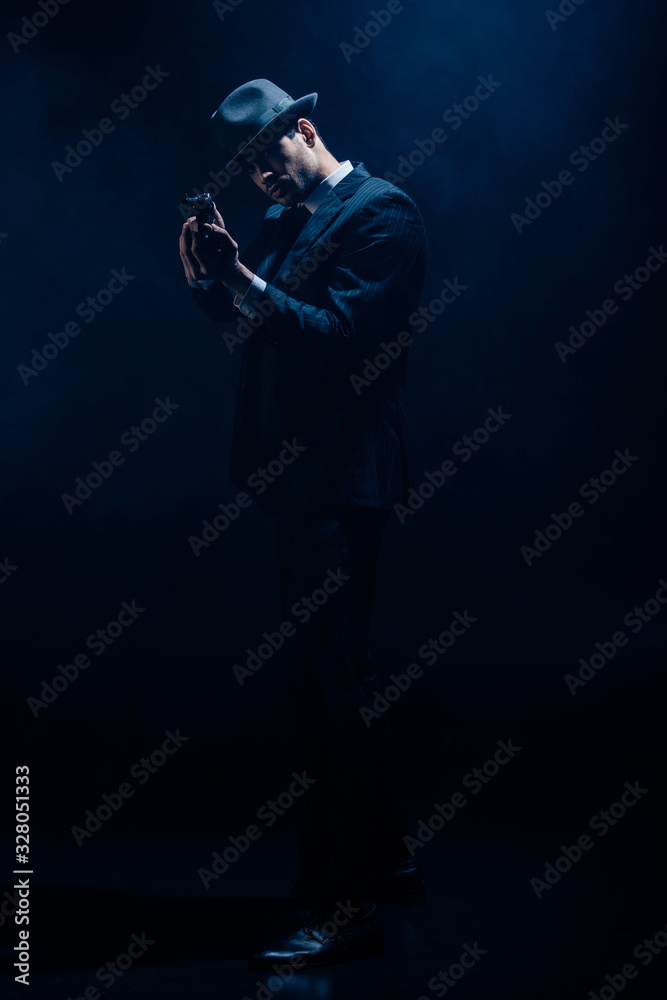 Gangster with clenched hands aiming weapon on dark blue background Gangster with clenched hands aiming weapon on dark blue background