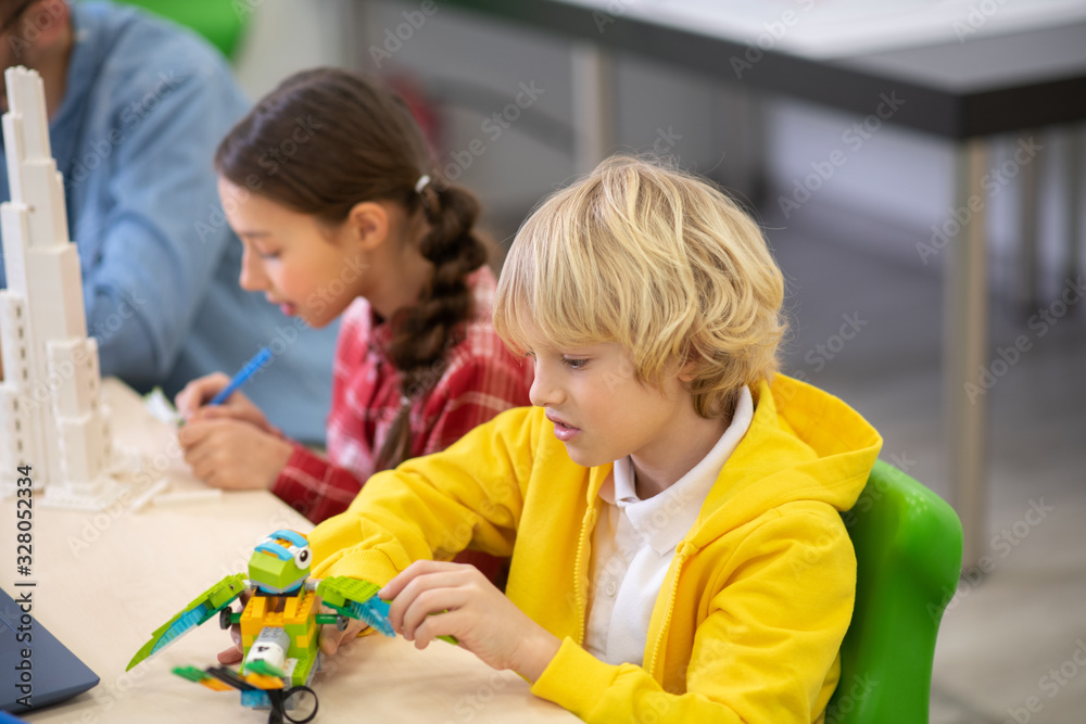 Obraz premium Boy playing with buildable bird, girl making notes