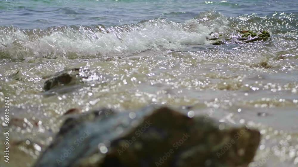 Low angle tracking view of waves breaking onto rocks on the beach Low angle tracking view of waves breaking onto rocks on the beach