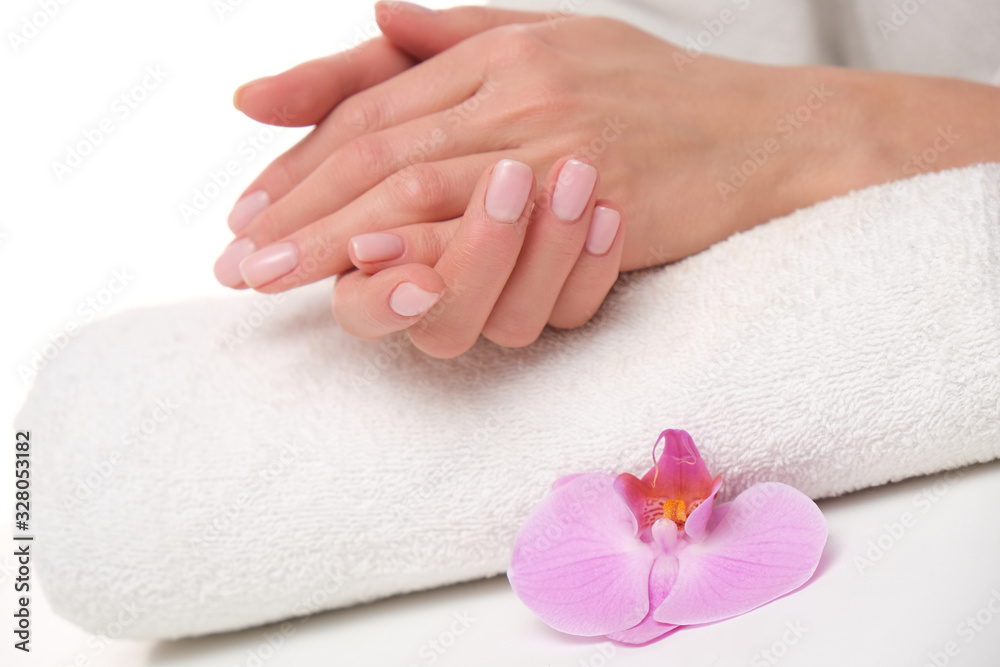 Beuatiful delicate manicure on female hands. The picture of hands lying on the white towel with purple orchid.