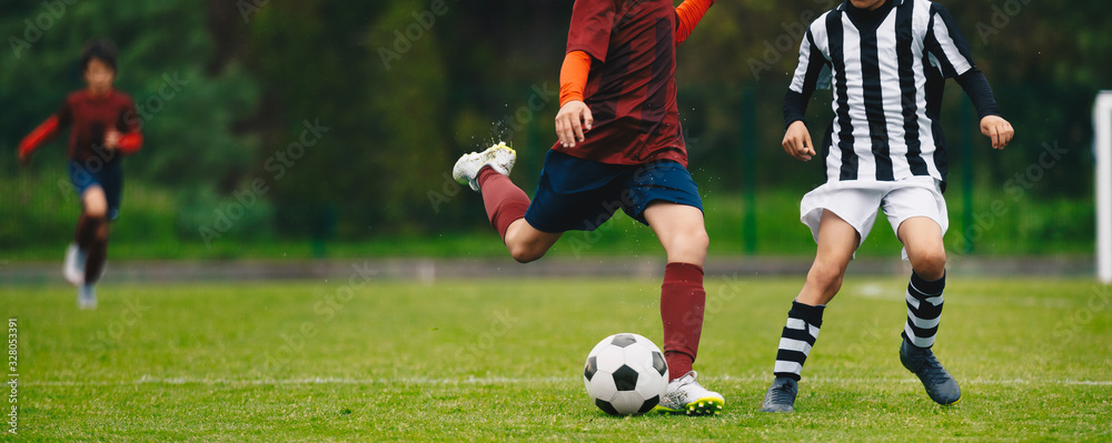 Young Athletes Kicking Soccer Ball on Wet Grass Field. Youth Football Players In Run Duel Young Athletes Kicking Soccer Ball on Wet Grass Field. Youth Football Players In Run Duel