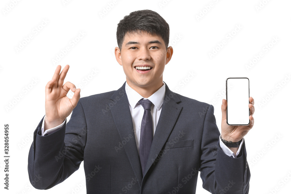 Young Asian businessman with mobile phone showing OK on white background Young Asian businessman with mobile phone showing OK on white background