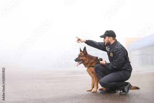 Male police officer with dog patrolling city street photo