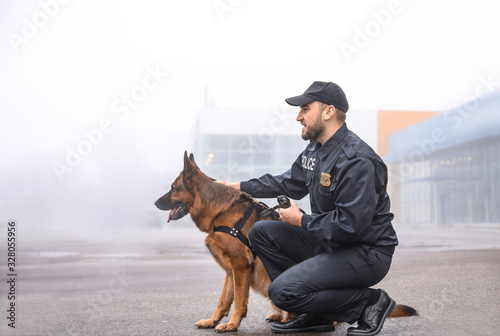 Fototapeta Male police officer with dog patrolling city street