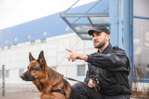 Male police officer with dog patrolling city street