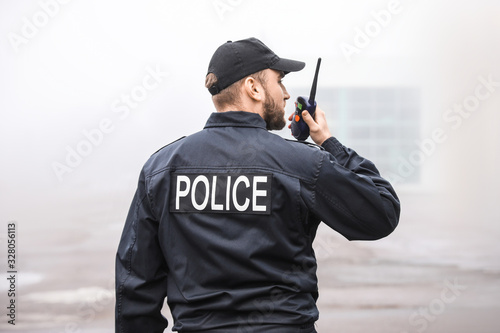 Fotografering Male police officer patrolling city street