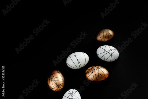 Easter goldenand white decorated eggs in nest on black background . Minimal easter concept copy space for text. Top horizontal view photo