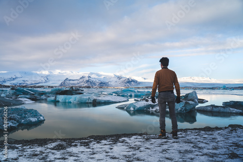 Jokulsarlon Glacier Lagoon in Iceland with Young Man Standing in Front of the Picture. Icelandic Cold Winter. Beautiful Nature Background.