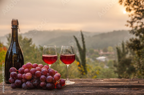 Wine Glasses And Bottle In Vineyard At Sunset