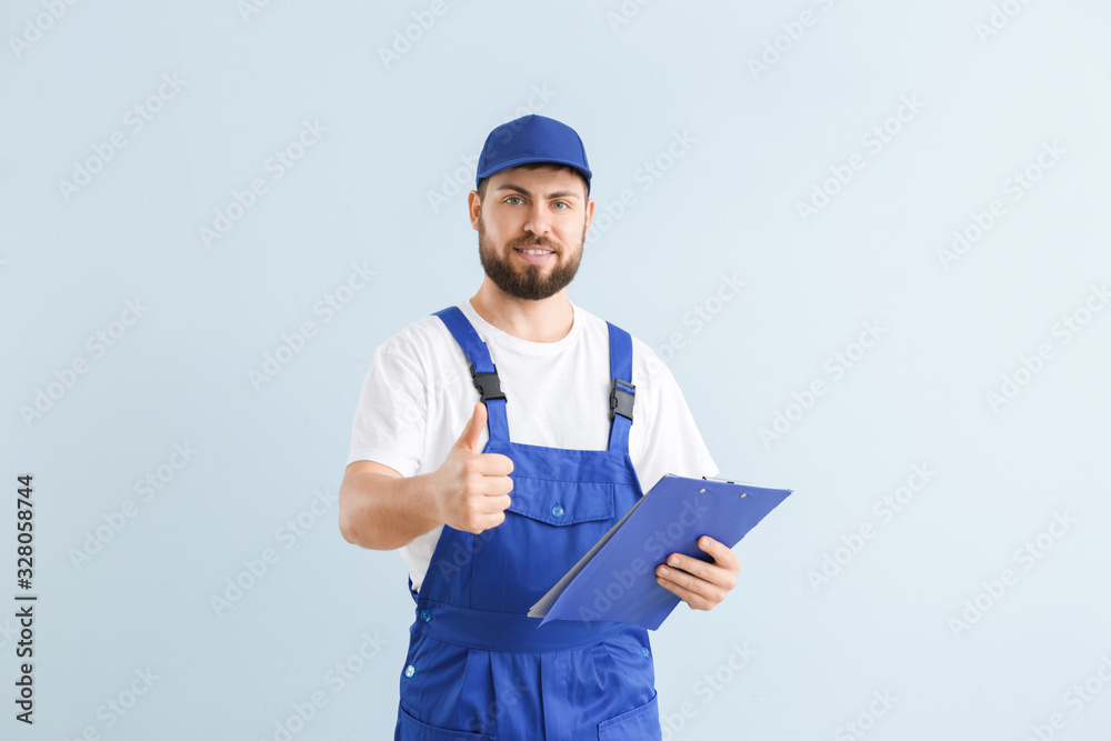 Handsome plumber showing thumb-up on color background Handsome plumber showing thumb-up on color background