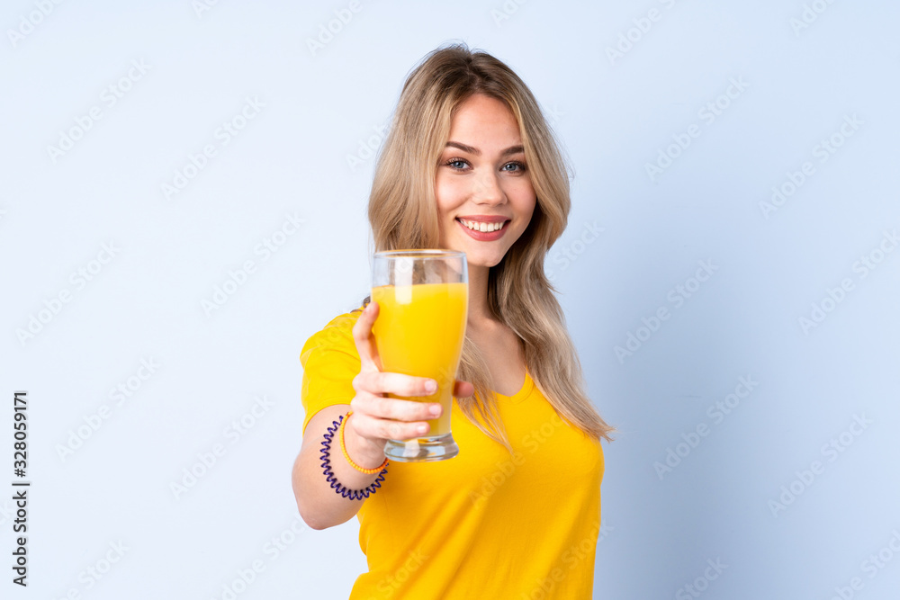 Teenager Russian girl holding an orange juice isolated on blue background with happy expression Teenager Russian girl holding an orange juice isolated on blue background with happy expression