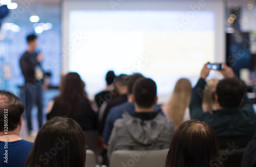 Business coach. Team leader teaches employees at a business meeting in a conference room. Speaker giving a talk at a corporate business seminar. Audience in hall with presenter in lecture photo.