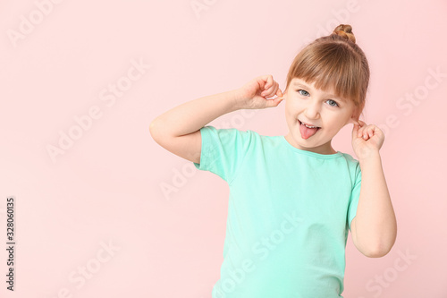 Funny grimacing little girl on color background