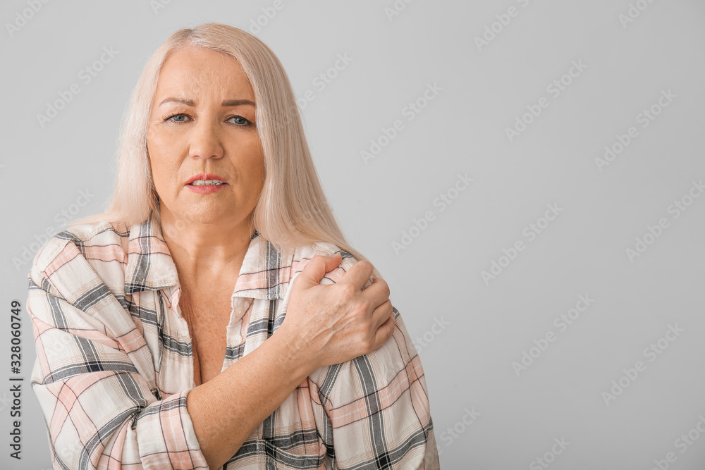 Senior woman suffering from Parkinson syndrome on grey background