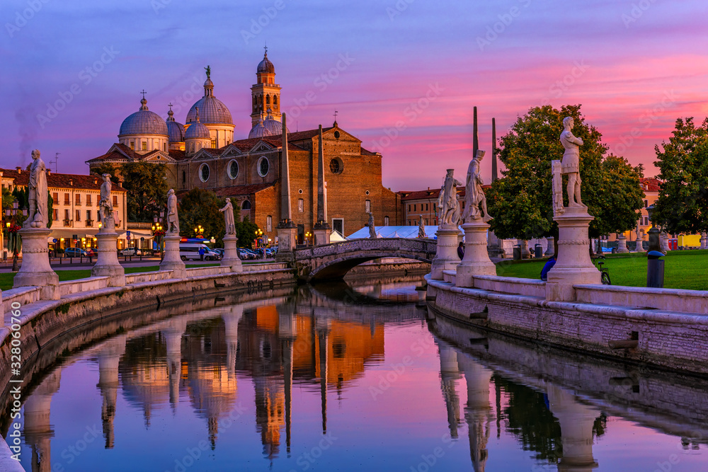 View of canal with statues on square Prato della Valle and Basilica Santa Giustina in Padova (Padua), Veneto, Italy. Sunset cityscape of Padua.