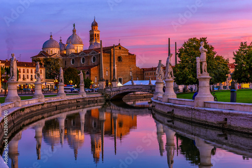 View of canal with statues on square Prato della Valle and Basilica Santa Giustina in Padova (Padua), Veneto, Italy. Sunset cityscape of Padua.