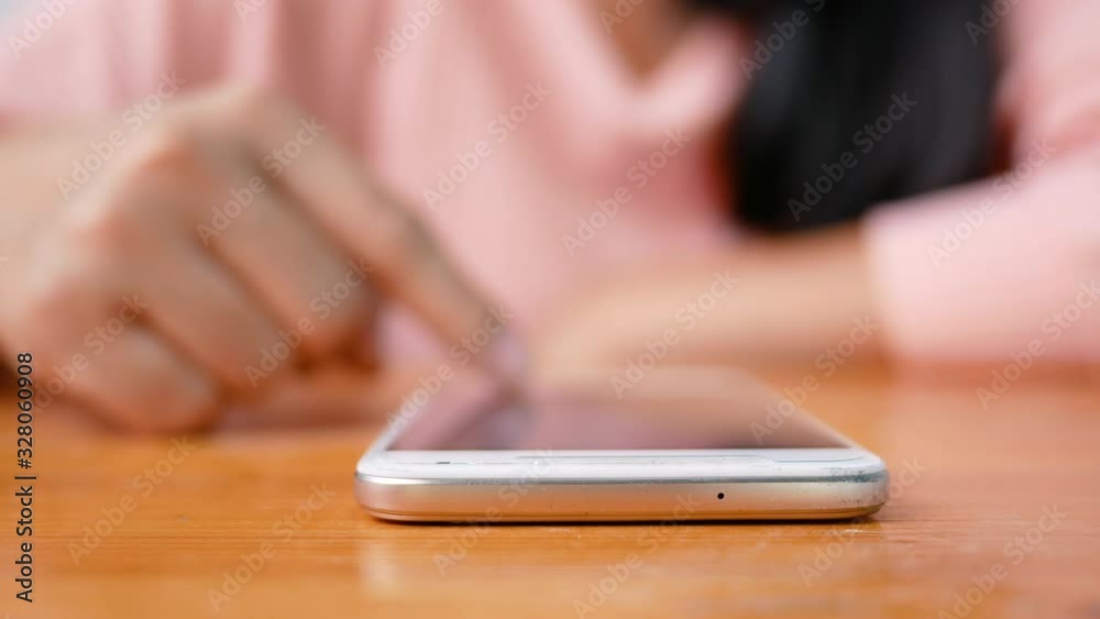 Close up of Asian young woman using smartphone sitting in living room on vacation day. Close up of Asian young woman using smartphone sitting in living room on vacation day.