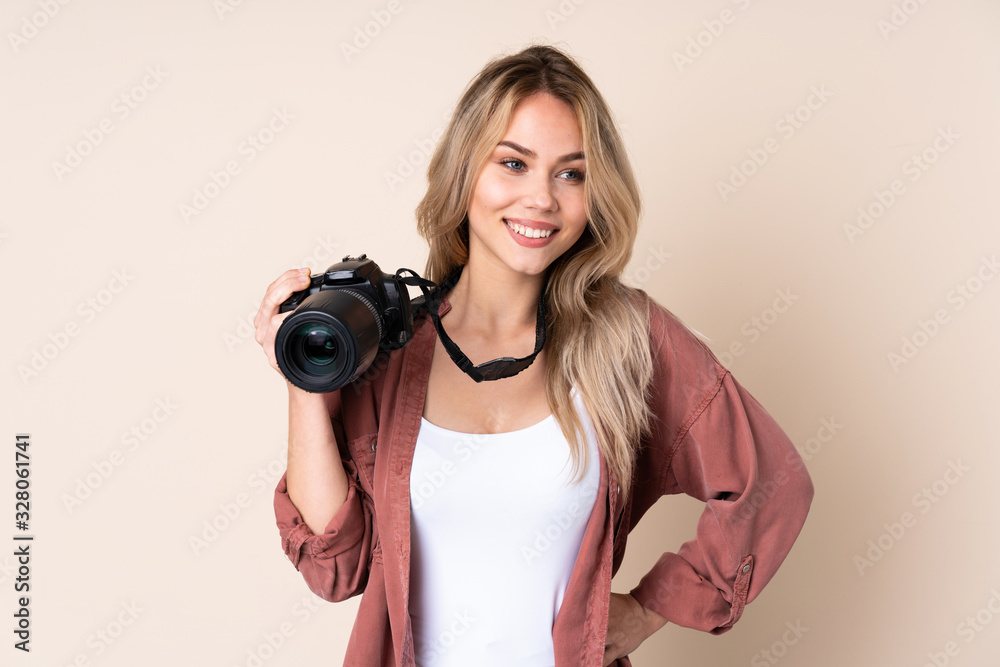 Young photographer girl over isolated background posing with arms at hip and smiling Young photographer girl over isolated background posing with arms at hip and smiling